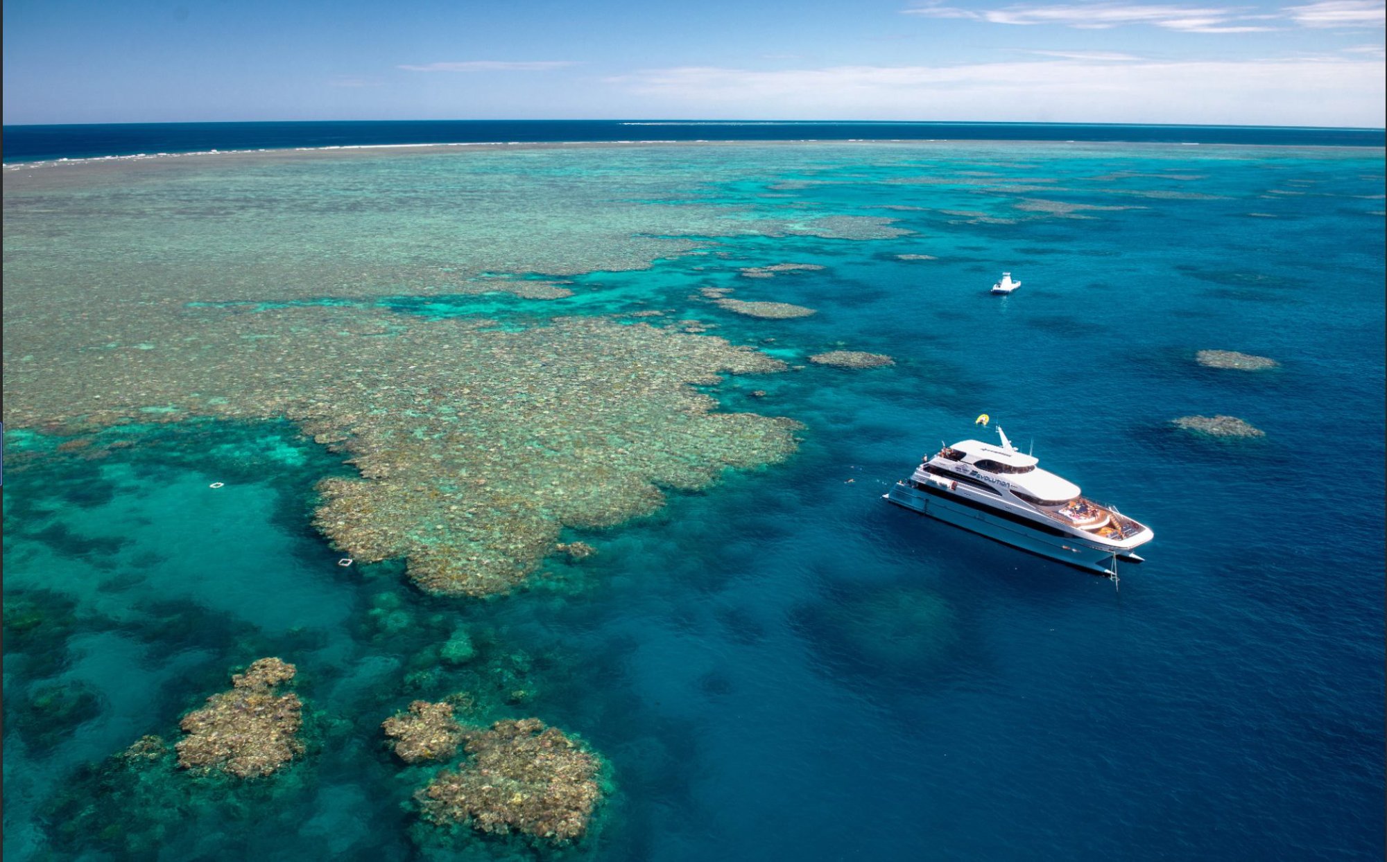 Aerial view of luxury catamaran anchored at Great Barrier Reef coral formations turquoise water Queensland Australia